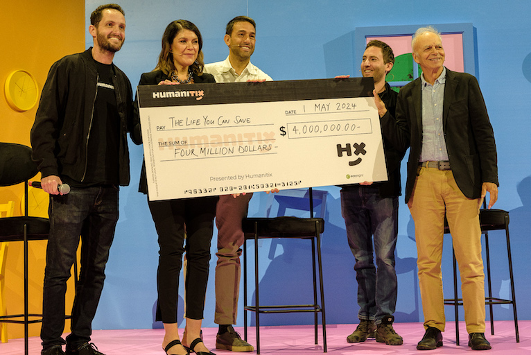 Humanitix cofounder Adam McCurdie presents The Life You Can Save director of philanthropy Louise Pfeiffer and co-CEO Andrea La Mesa with a $4 million donation, alongside his cofounder Josh Ross and ethicist and philosopher Peter Singer.