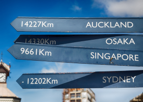 Street signs pointing to Auckland, Osaka, Singapore and Sydney